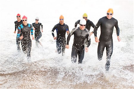 Triathletes in wetsuits running in waves Foto de stock - Sin royalties Premium, Código: 6113-06754049