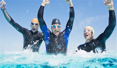 Triathletes in wetsuits splashing in waves Stock Photo - Premium Royalty-Free, Code: 6113-06754051