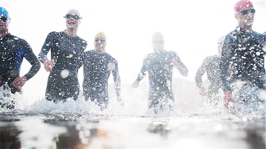 Triathletes in wetsuits running in waves Foto de stock - Sin royalties Premium, Código de la imagen: 6113-06754056