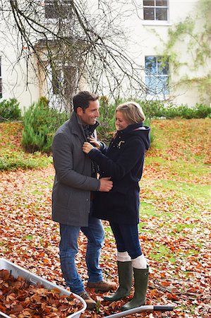 Smiling couple standing in autumn leaves Stock Photo - Premium Royalty-Free, Code: 6113-06720278