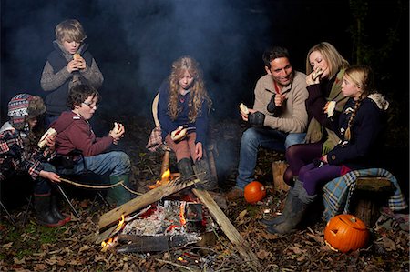 Family eating around campfire at night Photographie de stock - Premium Libres de Droits, Code: 6113-06720225