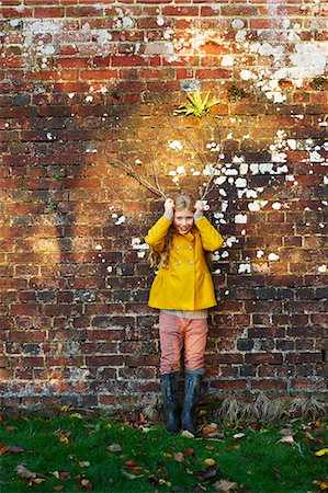 people stand in front brick wall - Girl holding branches like antlers outdoors Foto de stock - Sin royalties Premium, Código: 6113-06720230