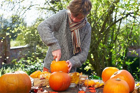 pumpkin garden - Teenage boy carving pumpkins outdoors Stock Photo - Premium Royalty-Free, Code: 6113-06720317