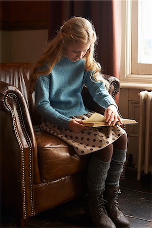 Girl reading book in armchair Stock Photo - Premium Royalty-Free, Code: 6113-06720323