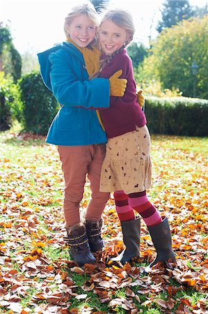 rain boots for girls - Girls hugging in autumn leaves Stock Photo - Premium Royalty-Free, Code: 6113-06720325