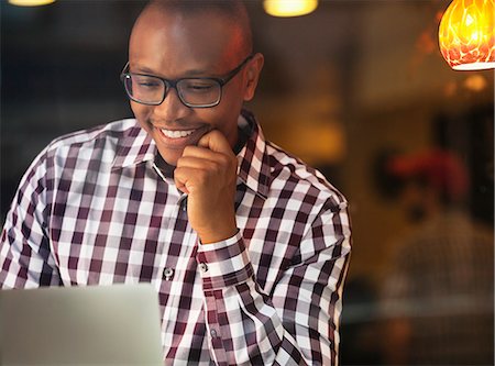 Smiling man reading laptop indoors Stock Photo - Premium Royalty-Free, Code: 6113-06720440