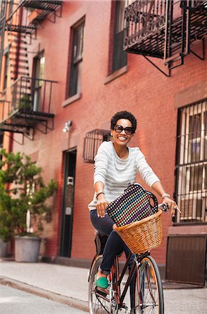 Woman riding bicycle on city street Stock Photo - Premium Royalty-Free, Code: 6113-06720470