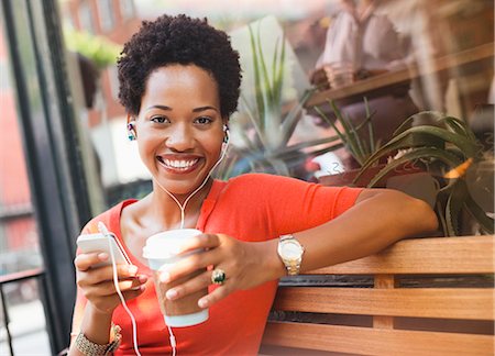 Woman listening to earphones by coffee shop Stock Photo - Premium Royalty-Free, Code: 6113-06720431