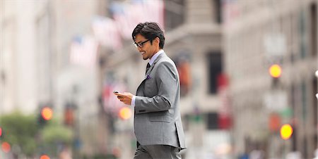Businessman using cell phone on city street Stock Photo - Premium Royalty-Free, Code: 6113-06720551
