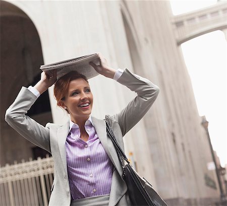 rain walk - Businesswoman covering hair with newspaper Stock Photo - Premium Royalty-Free, Code: 6113-06720557