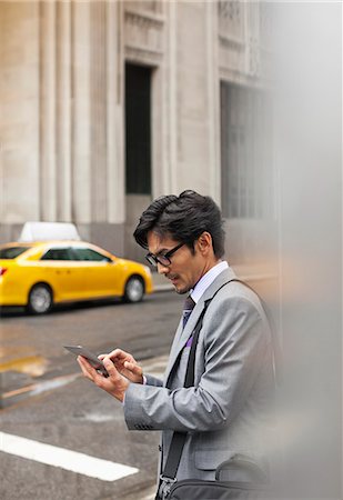 simsearch:6113-06720509,k - Businessman using tablet computer on city street Photographie de stock - Premium Libres de Droits, Code: 6113-06720563