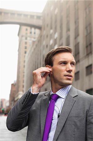 Businessman listening to earphones on city street Stock Photo - Premium Royalty-Free, Code: 6113-06720560