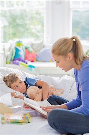 sad child hug mother - Mother reading to son in bed Stock Photo - Premium Royalty-Free, Code: 6113-06720573