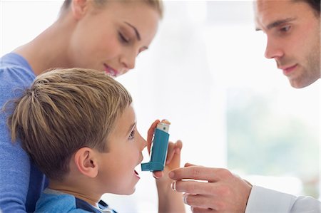 Parents giving son asthma inhaler Stock Photo - Premium Royalty-Free, Code: 6113-06720590