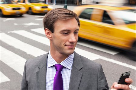 Businessman using cell phone on city street Stock Photo - Premium Royalty-Free, Code: 6113-06720520