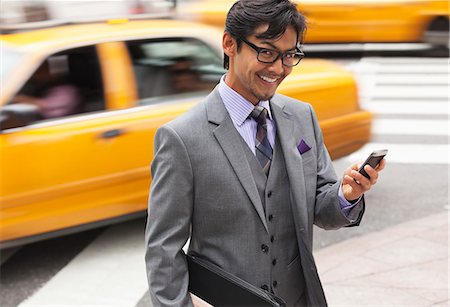 Businessman using cell phone on city street Stock Photo - Premium Royalty-Free, Code: 6113-06720530