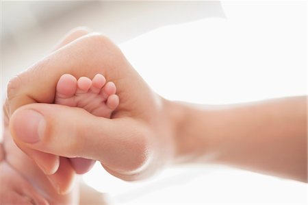 Mother cradling newborn baby's foot Photographie de stock - Premium Libres de Droits, Code: 6113-06720640