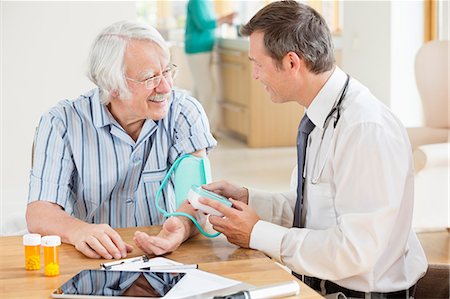 Doctor testing older patient's blood pressure at house call Stock Photo - Premium Royalty-Free, Code: 6113-06720651