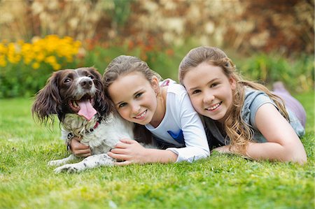 family backyard relaxing - Smiling girls relaxing with dog on lawn Stock Photo - Premium Royalty-Free, Code: 6113-06720865