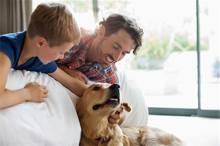 family with one child caucasian - Father and son petting dog on sofa Stock Photo - Premium Royalty-Free, Code: 6113-06720871
