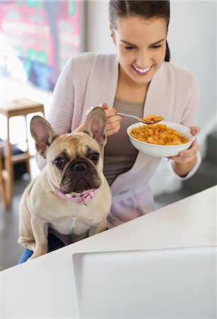 french bulldog not puppy - Woman eating cereal with dog on lap Stock Photo - Premium Royalty-Free, Code: 6113-06720953