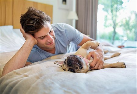 pet owners - Man petting dog on bed Foto de stock - Sin royalties Premium, Código: 6113-06720962