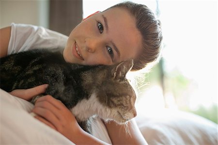domestic cat - Girl petting cat on bed Stock Photo - Premium Royalty-Free, Code: 6113-06720984