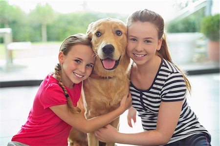 Smiling girls hugging dog indoors Stock Photo - Premium Royalty-Free, Code: 6113-06720985