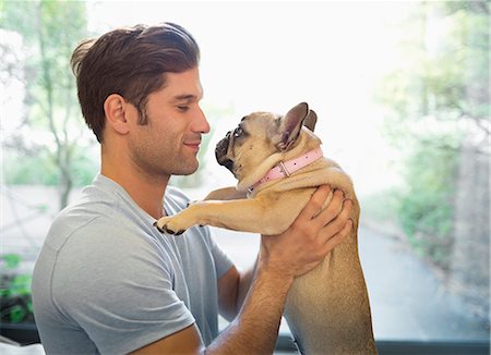 simsearch:6113-06720906,k - Smiling man holding dog indoors Photographie de stock - Premium Libres de Droits, Code: 6113-06720906