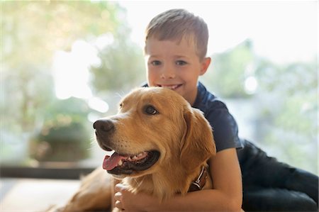 dog and boy - Smiling boy hugging dog indoors Stock Photo - Premium Royalty-Free, Code: 6113-06720913