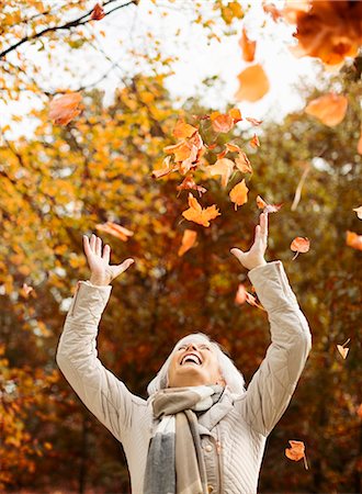 Older woman playing in autumn leaves Stock Photo - Premium Royalty-Free, Code: 6113-06721149