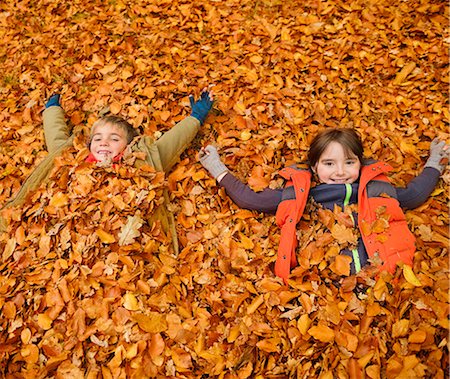 Children laying in autumn leaves Photographie de stock - Premium Libres de Droits, Code: 6113-06721229