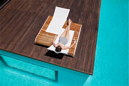 Woman sunbathing at poolside Foto de stock - Sin royalties Premium, Código: 6113-06898776