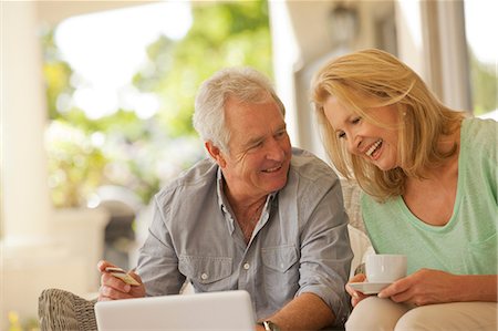 seniors surfing - Smiling couple drinking coffee and shopping online on patio Stock Photo - Premium Royalty-Free, Code: 6113-06898865