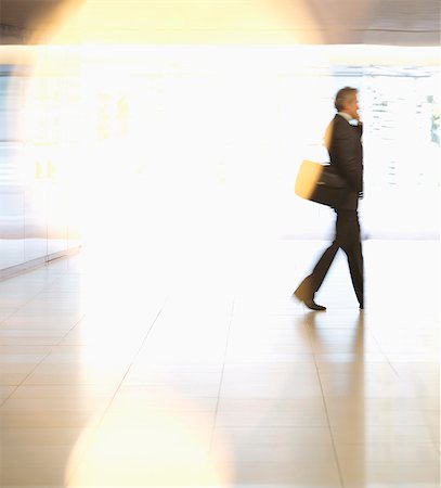 person talking on cell phone motion blur - Businessman walking in lobby Stock Photo - Premium Royalty-Free, Code: 6113-06898991