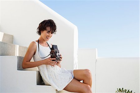 people looking up at camera - Smiling woman holding vintage camera on stairs Foto de stock - Sin royalties Premium, Código: 6113-06898919