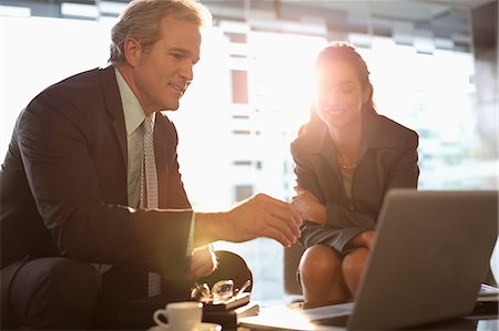 person on computer - Businessman and businesswoman using laptop in lobby Stock Photo - Premium Royalty-Free, Code: 6113-06899057