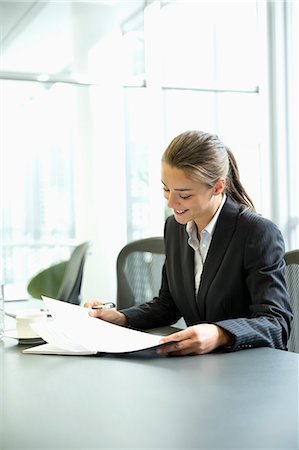 Businesswoman reading paperwork in conference room Stock Photo - Premium Royalty-Free, Code: 6113-06899082