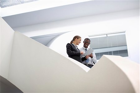 Businessman and businesswoman using digital tablet on modern staircase Foto de stock - Sin royalties Premium, Código: 6113-06899099