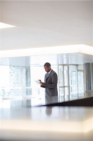 Businessman using digital tablet in lobby Stock Photo - Premium Royalty-Free, Code: 6113-06899019