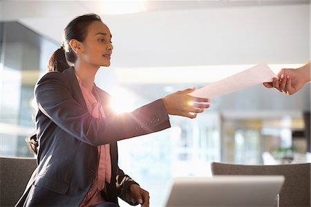 Businesswoman reaching for paperwork Photographie de stock - Premium Libres de Droits, Code: 6113-06899116