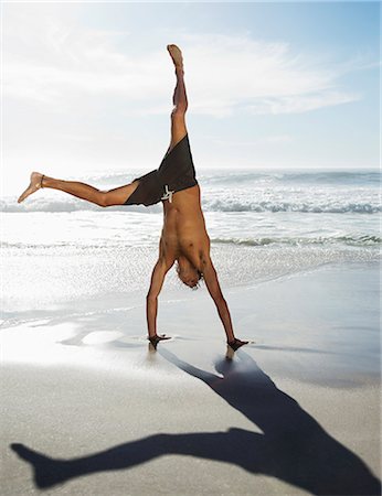 Man in swim trunks doing handstand on beach Foto de stock - Sin royalties Premium, Código: 6113-06899252