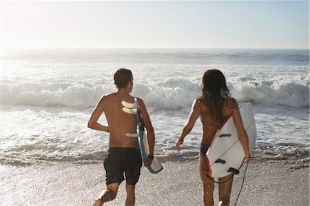 Couple running with surfboards toward ocean Photographie de stock - Premium Libres de Droits, Code: 6113-06899259