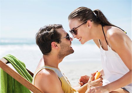 simsearch:6113-06899268,k - Happy couple rubbing sunscreen-covered noses on beach Stock Photo - Premium Royalty-Free, Code: 6113-06899208