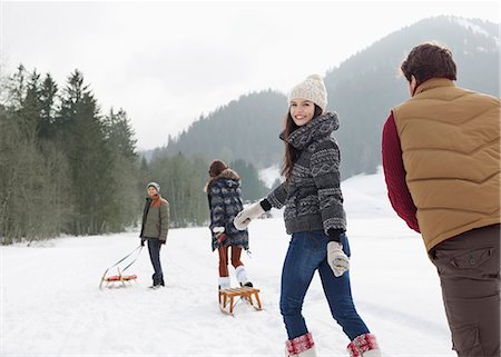 Friends pulling sleds in snowy field Stock Photo - Premium Royalty-Free, Code: 6113-06899340
