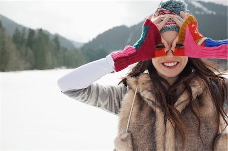 Portrait of smiling woman circling eyes with fingers in snowy field Photographie de stock - Premium Libres de Droits, Code: 6113-06899333