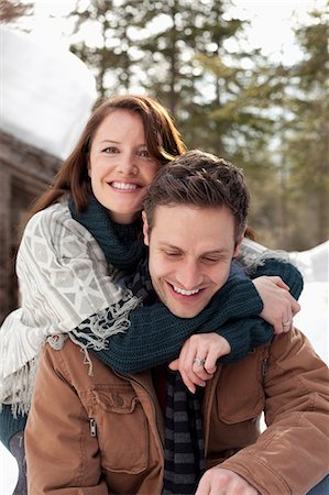 snow couple smiling hugging - Portrait of hugging couple outside snowy cabin Stock Photo - Premium Royalty-Free, Code: 6113-06899467