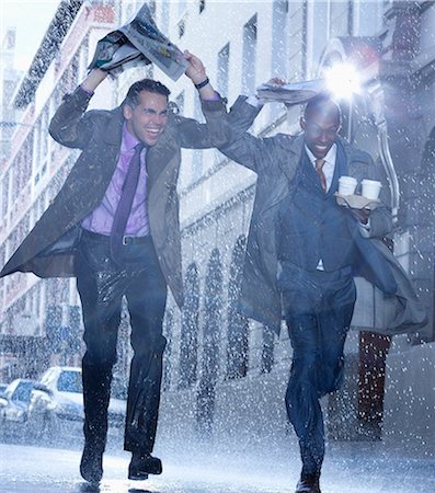 Businessmen carrying coffee and covering heads with newspaper in rain Foto de stock - Sin royalties Premium, Código: 6113-06899552
