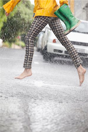 Barefoot woman running across street in rain Foto de stock - Sin royalties Premium, Código: 6113-06899554