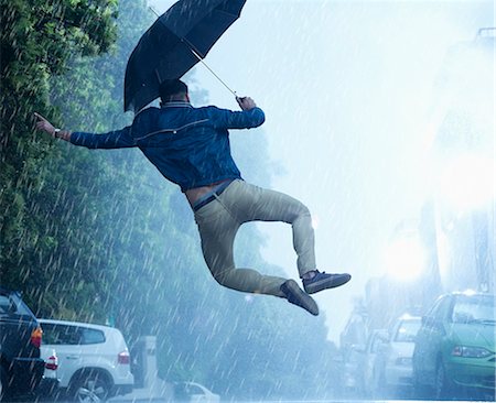 people with umbrella pictures - Man with umbrella jumping in rain Stock Photo - Premium Royalty-Free, Code: 6113-06899560